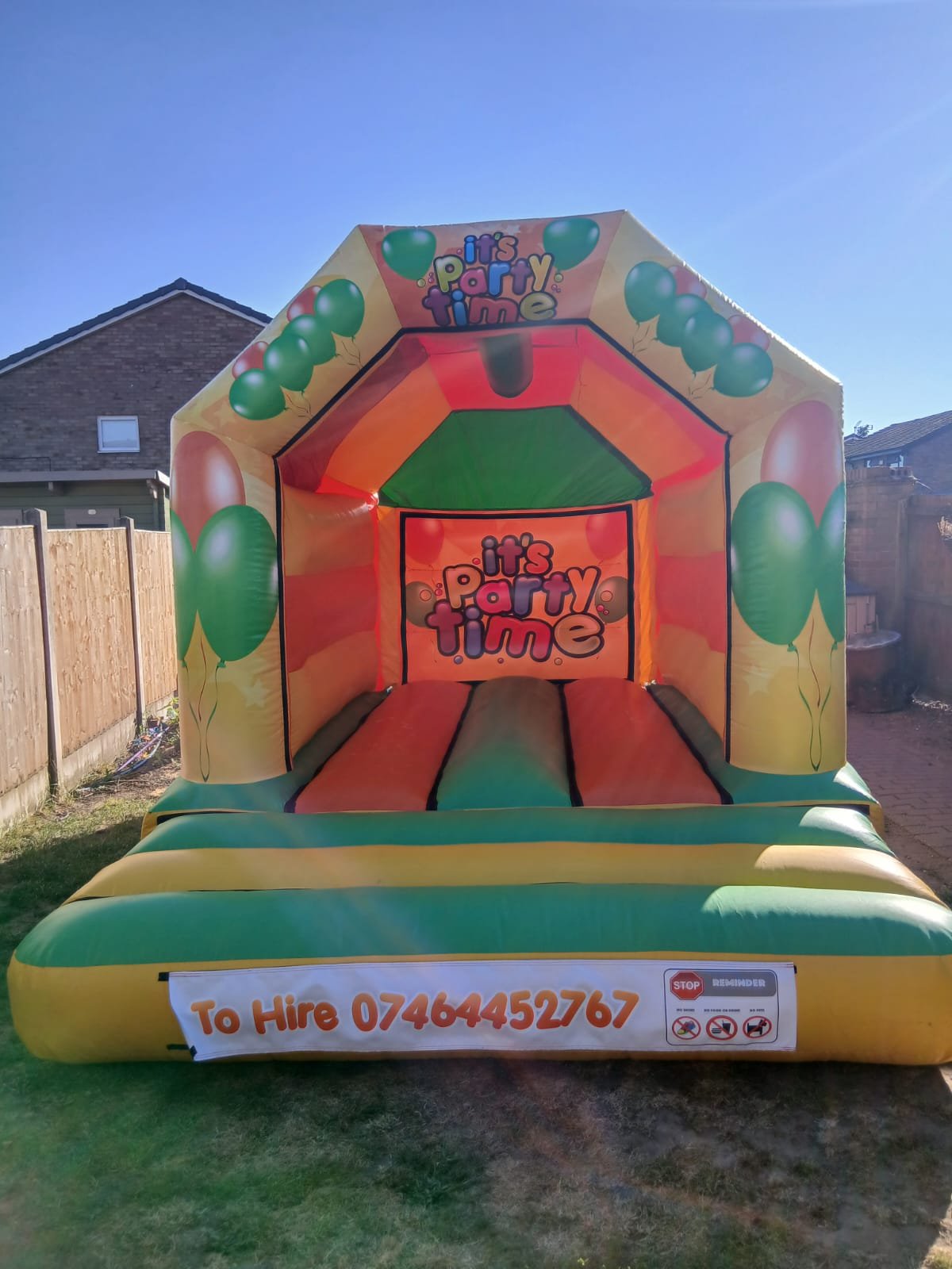 Party Time bouncy castle, bright green, orange and yellow, set up and ready